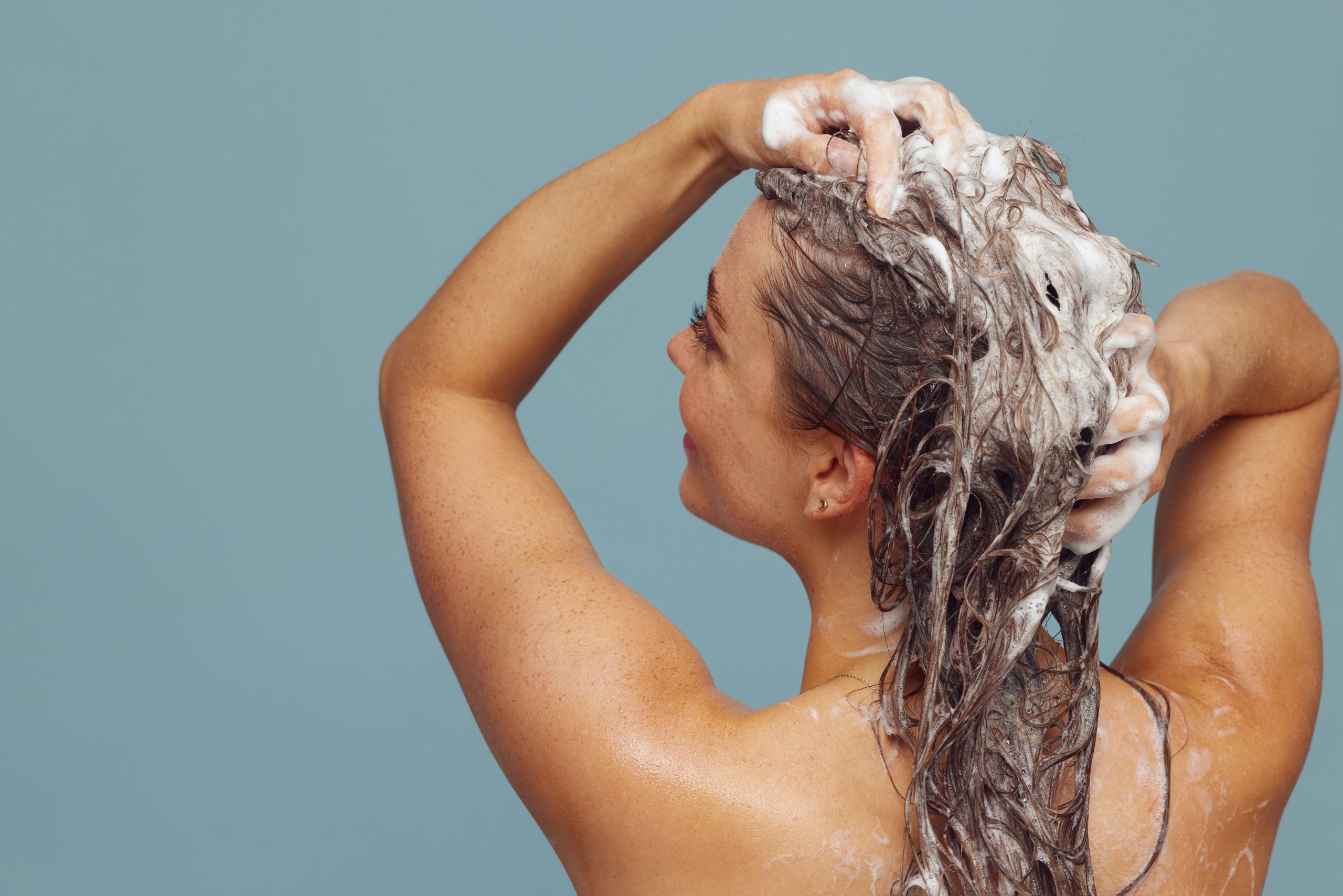 Femme cheveux longs se lavant avec shampoing bio