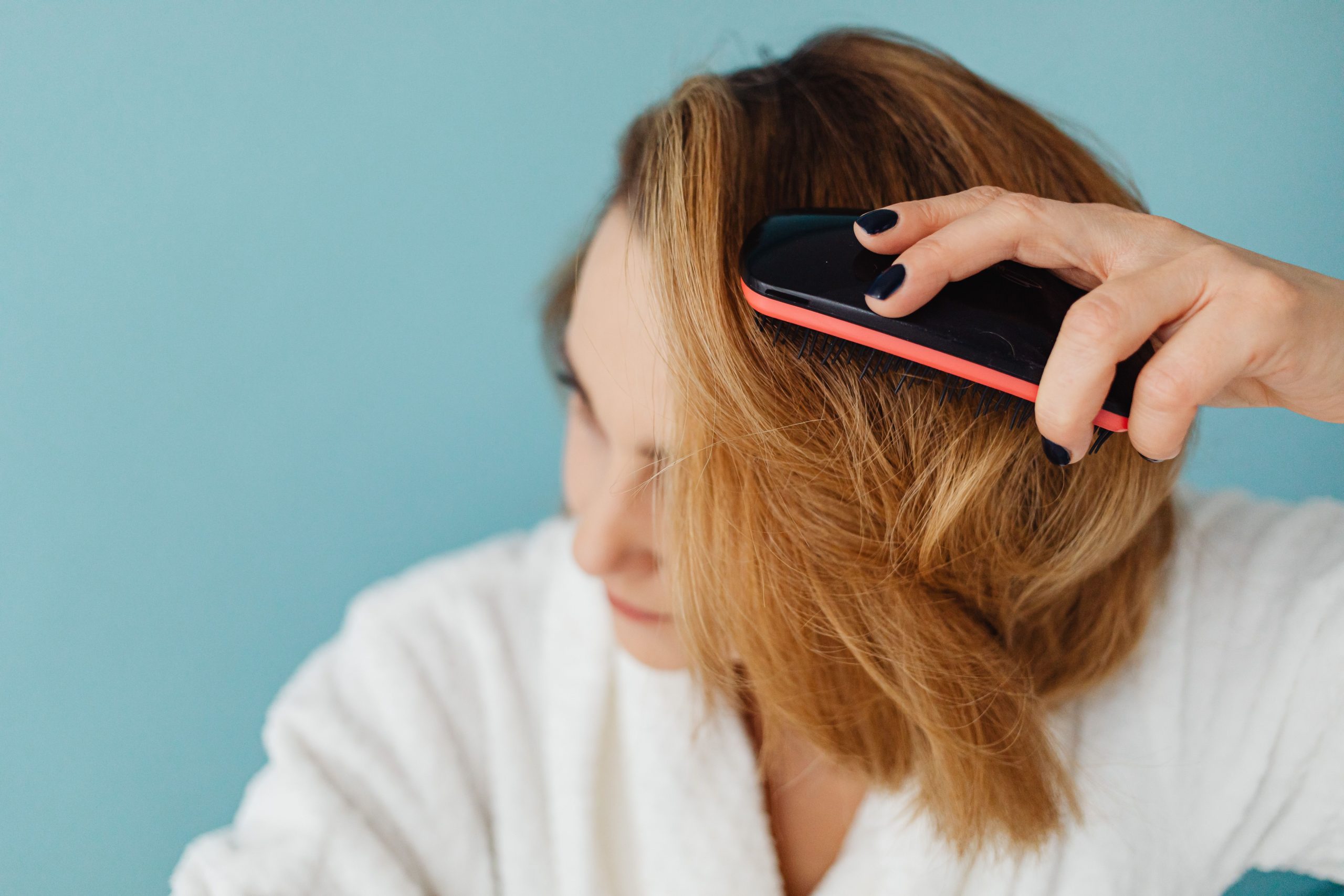 Femme en peignoir démêlant cheveux quotidiennement