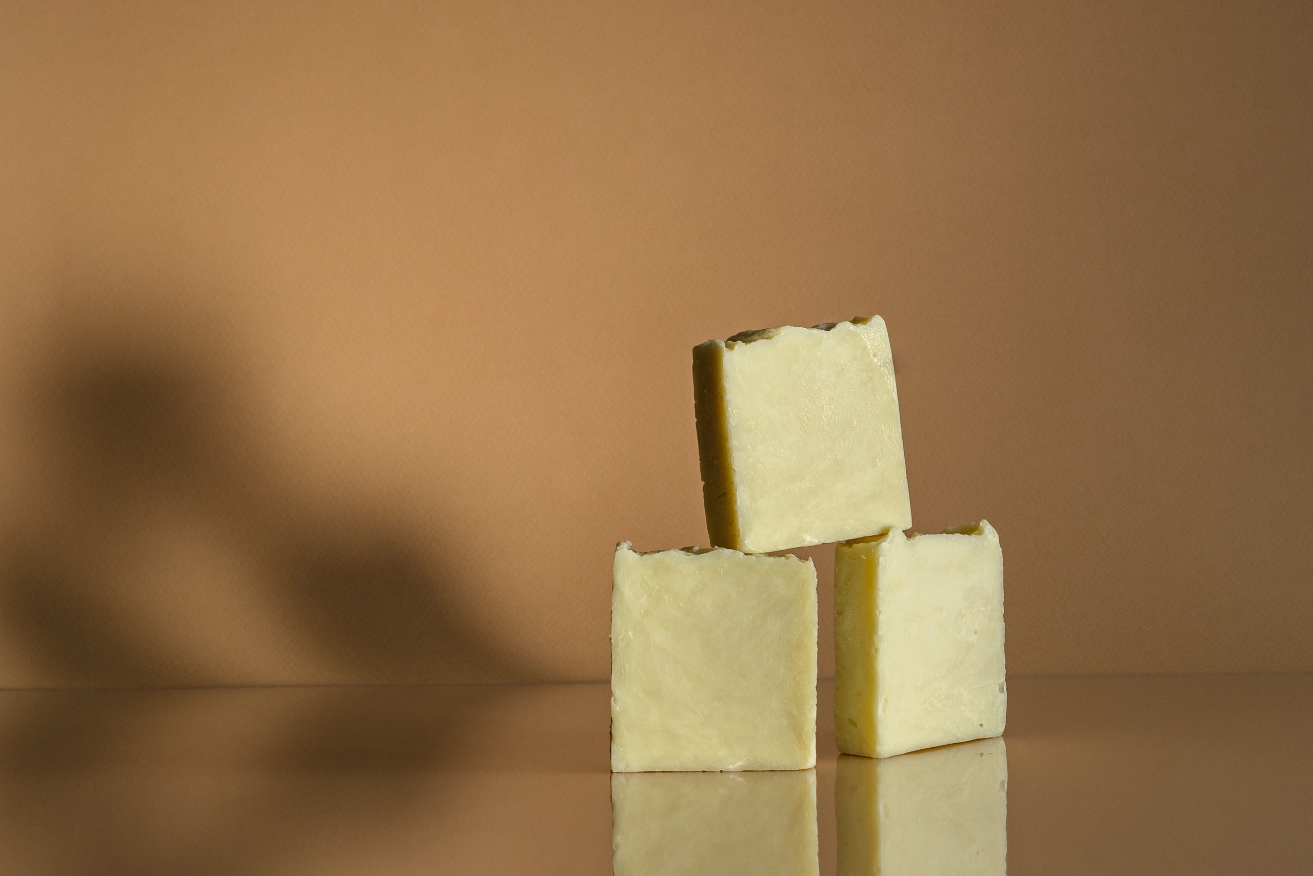 Trois savons solides artisanaux empilés surface brillante