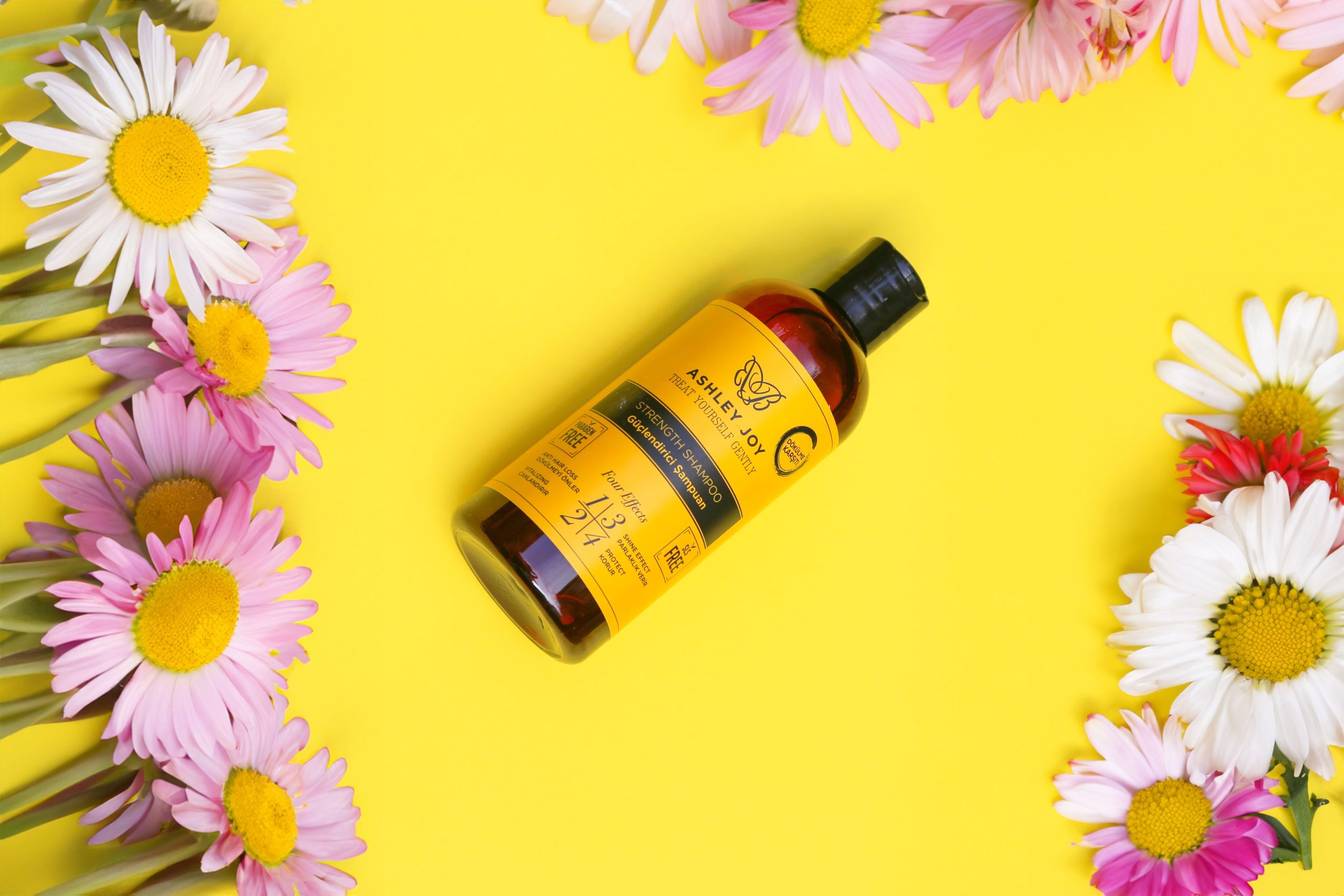 Flacon de shampoing jaune entouré de marguerites